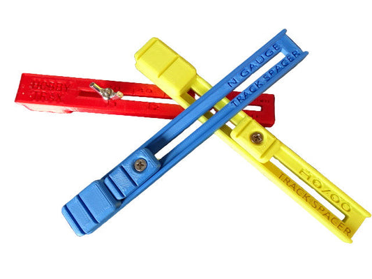 Three plastic track spacers in red, blue, and yellow for H0, 00, TT and N gauge